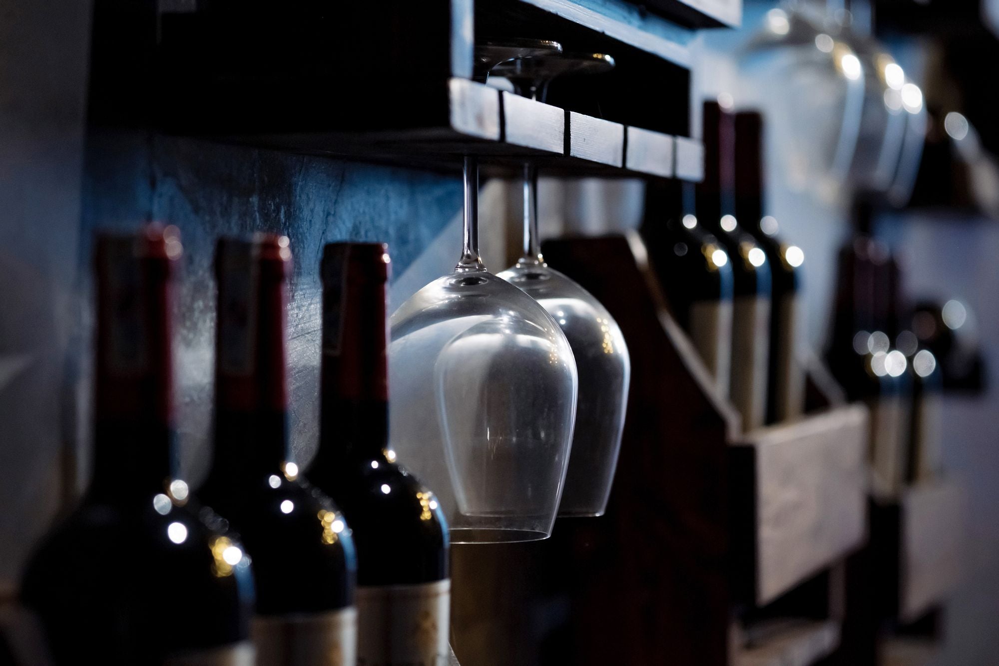 Sticle și pahare de vin pe rafturi de lemn